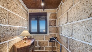Un bagno con pareti in pietra, un mobile lavabo in legno, una finestra e un portascopevoli.