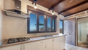 Una cucina con gas, mobili, una finestra e una porta che conduce al bagno.
