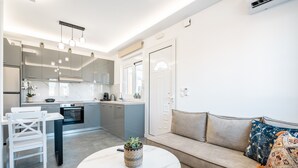 A modern kitchen with a dining area, a sofa, and a small table with a plant. - Apartment 'Velvet  1' with Mountain View, Wi-Fi and Air Conditioning (RHODES)