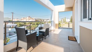 A balcony with wicker furniture, a glass table, and a view of the neighborhood. - Apartment 'Velvet  1' with Mountain View, Wi-Fi and Air Conditioning (RHODES)