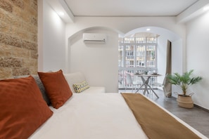 Une chambre d’hôtel avec un lit, une plante en pot et un balcon équipé d’une table et de chaises.