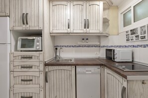 Una cocina con armarios de madera blanca, un microondas, un tostador y un lavavajillas.