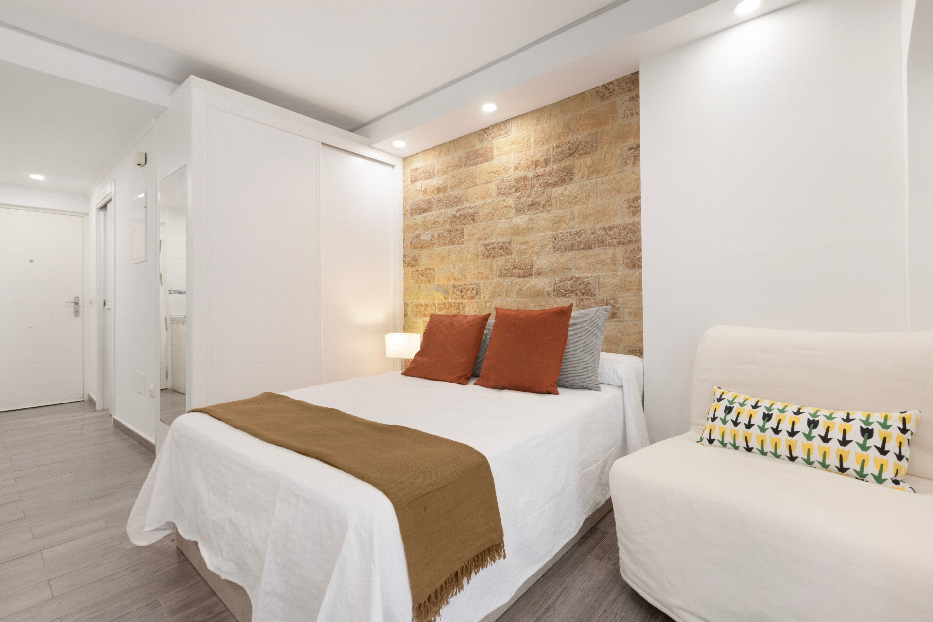 Une chambre avec un lit, un canapé, un mur en briques et une porte.