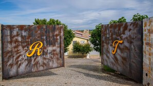 Een robuust metalen hek met de letters 'R' en 'T' en een stenen muur met gegraveerde tekst.