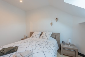 Une chambre à coucher comprenant un lit, des tables de chevet, une lampe et un luminaire fixé au mur.