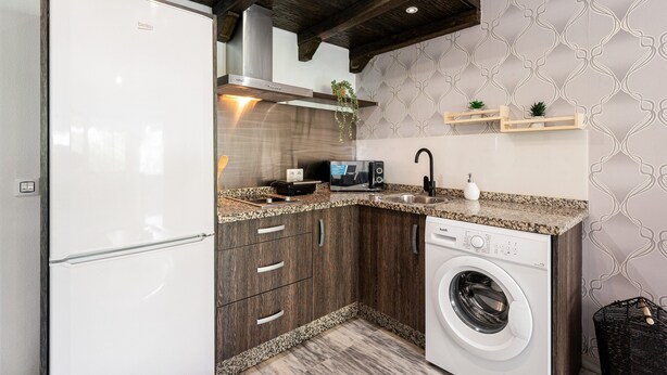 A compact kitchen with a built-in washing machine, a microwave, and a sink. - Apartment 'Apartamento Mefistofeles' with Private Terrace, Wi-Fi & Air Conditioning (Málaga)