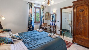 Een slaapkamer met een bed, een houten kledingkast, een spiegel en een raam met gordijnen.