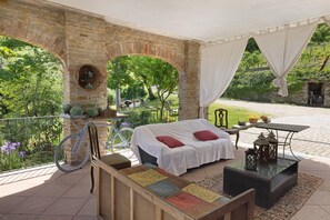 A covered outdoor seating area with a bed, a table, and a bicycle. - Apartment 'Nebbiolo' with Shared Terrace, Shared Garden and Wi-Fi (Mango)