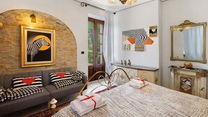 Ein Zimmer mit einem Bett, einer Couch, einem Kamin und Kunstwerken an den Wänden.