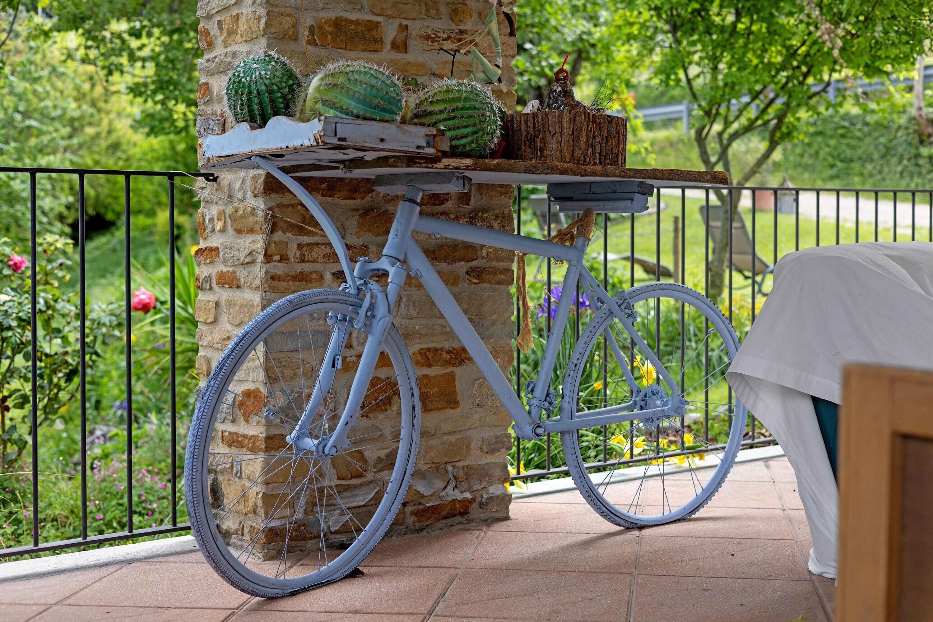 Una bicicleta estacionada junto a un muro de piedra con una cesta que contiene cactus.