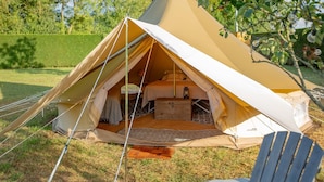 Ein Zelt aus Stoff mit einem Bett, einer Laterne und einer kleinen Holzkiste.