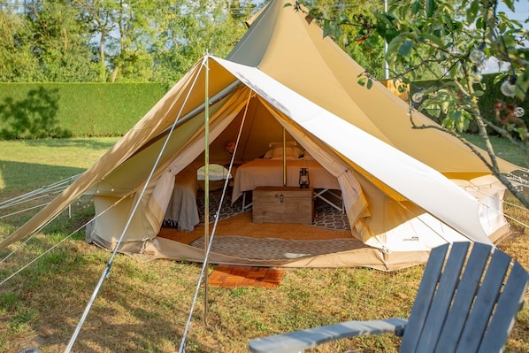 A canvas tent with a bed, a lantern, and a small wooden chest.