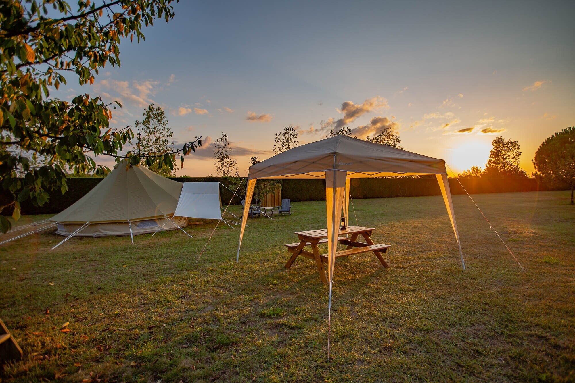 A camping site with a tent, a canopy, and a picnic table.