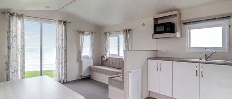 A compact kitchen with a dining area, a microwave, and a view of the sea.