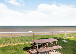A picnic table and a chain-link fence overlooking a beach. - Castaways Oyster 8 Sea View (Pet) (Bacton-on-Sea)
