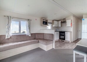Un espacio habitable pequeño con sofá, kitchenette y ventana con cortinas.