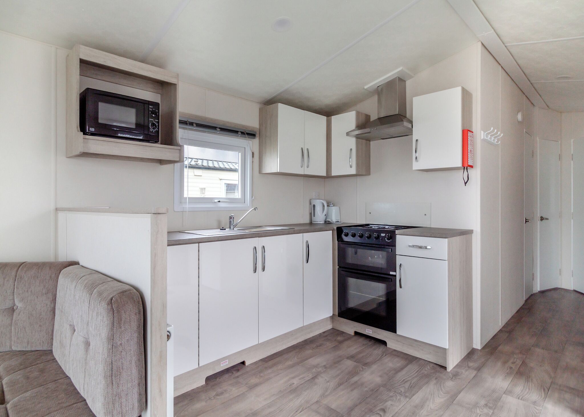 A compact kitchenette with a microwave, stove, sink, and cabinets.