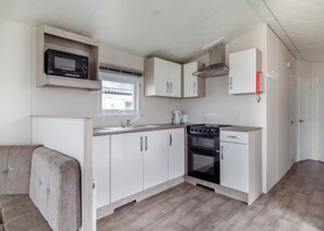 Una kitchenette compacta con microondas, estufa, lavabo y armarios.