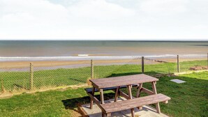 A picnic table and a chain-link fence overlooking a beach. - Castaways Oyster 8 Sea View (Pet) (Bacton-on-Sea)