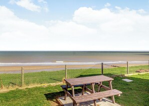 A picnic table and a chain-link fence overlooking a beach. - Castaways Oyster 8 Sea View (Pet) (Bacton-on-Sea)