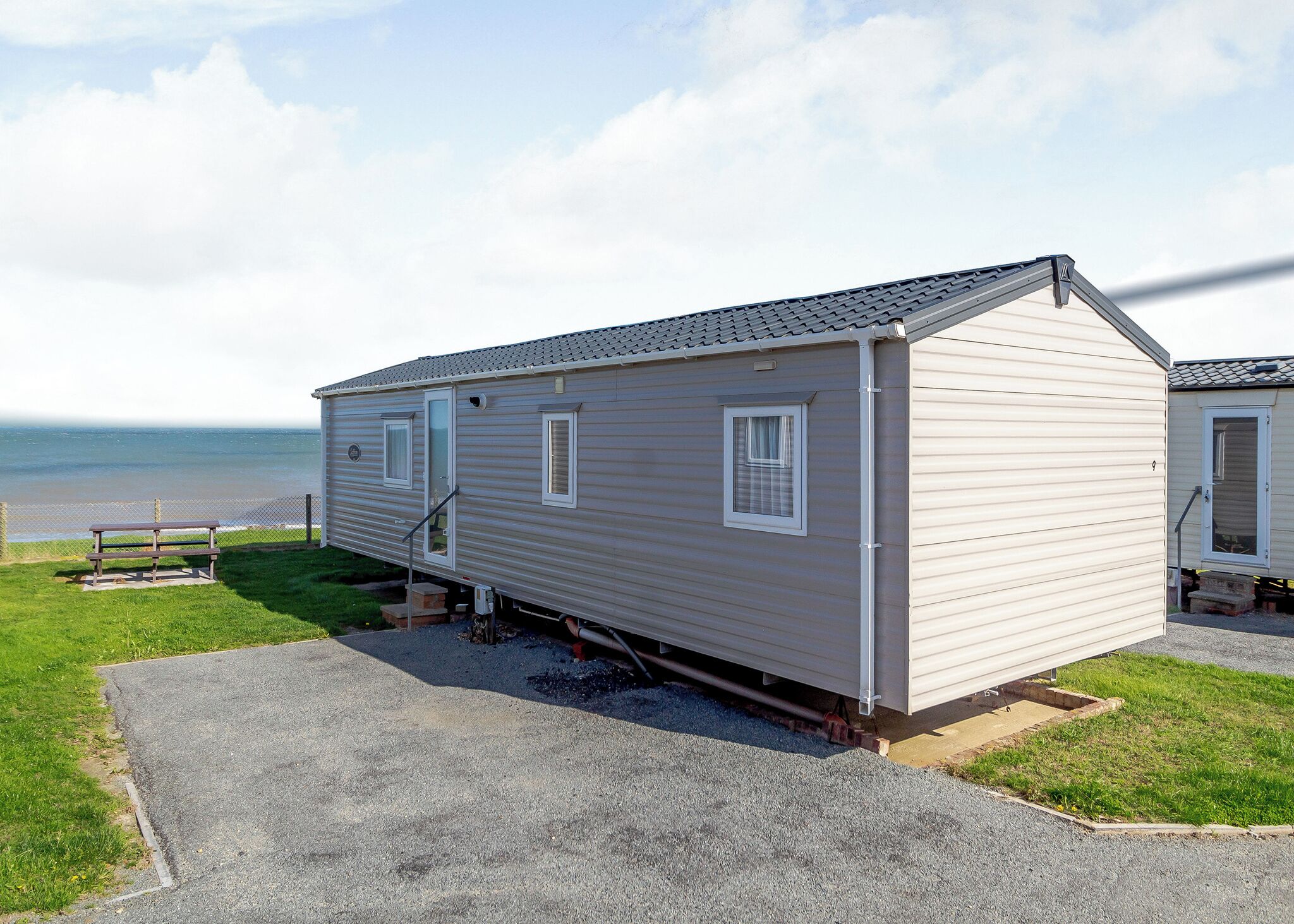A single-story mobile home with a covered porch, a small window, and a door.