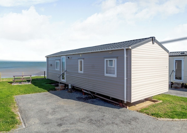 A single-story mobile home with a covered porch, a small window, and a door.