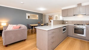 Una cocina moderna con armarios grises, una isla central y una zona de comedor con un sofá y una mesa grises.