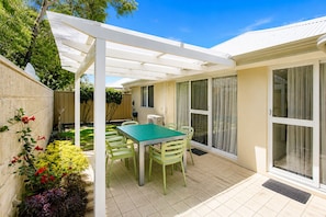 A patio with a table and chairs, a covered area, and a sliding glass door. - Salty Sands (Broadwater)