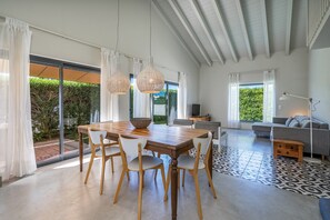 A spacious living area with a dining table, chairs, a sofa, and a patterned rug.