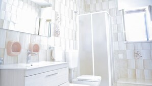 A modern bathroom with a white vanity, toilet, and shower enclosure.
