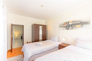 Een slaapkamer met twee bedden, een kledingkast, een schilderij en een nachtkastje met een lamp.