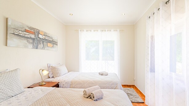 Una camera da letto con due letti, un comodino, una lampada e un quadro appeso al muro.