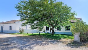Un edificio con un albero davanti, un cartello con del testo e un cielo sereno.