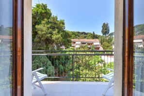 Un balcon donnant sur un immeuble et des arbres.