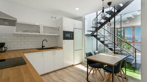 Una cocina moderna con armarios blancos, encimera de madera, microondas integrado y un refrigerador negro.