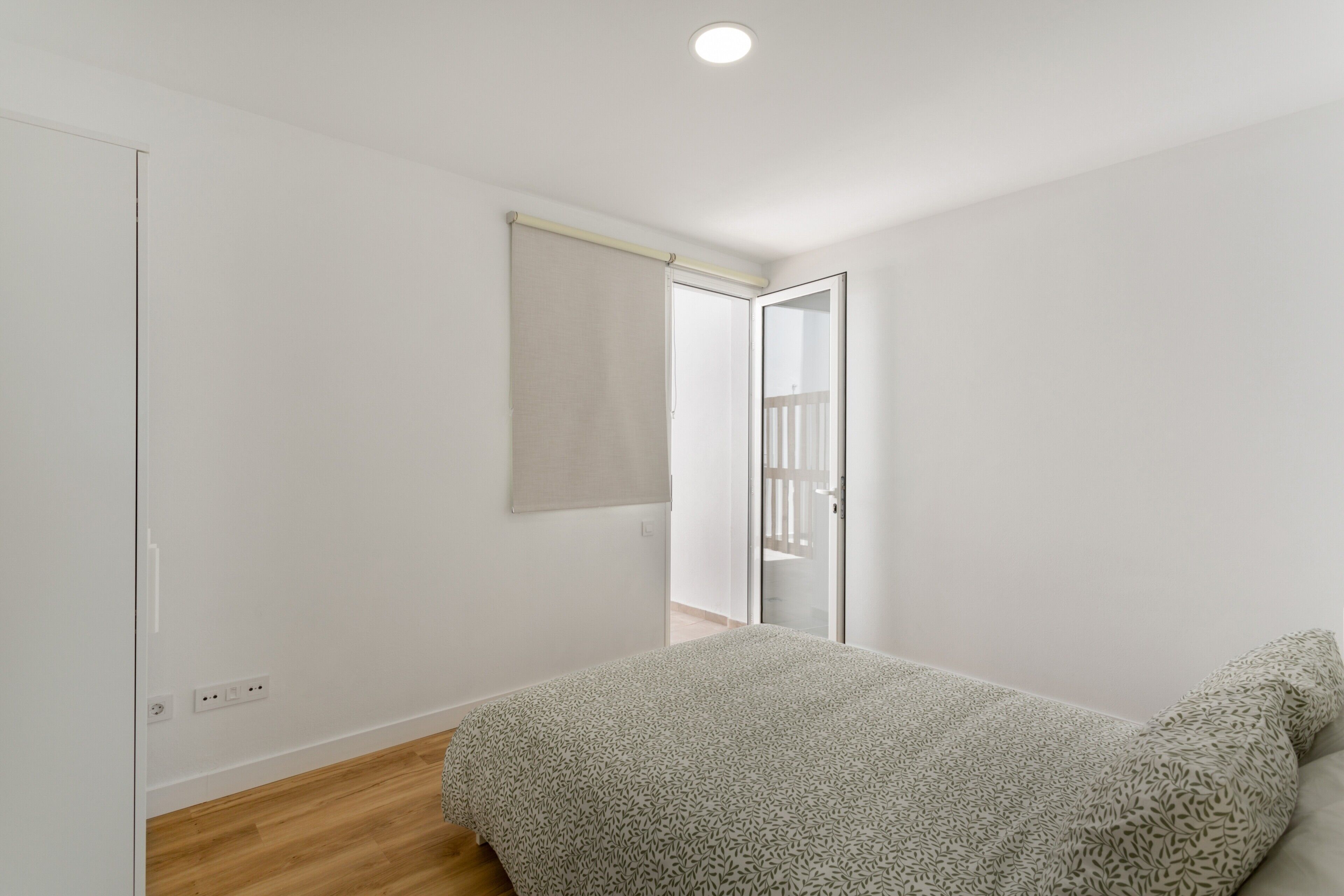 Een slaapkamer met een bed, een kast, een deur en een lamp.