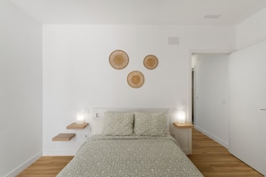Un dormitorio con cama, mesitas de noche y una lámpara fijada a la pared.