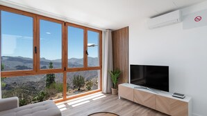Una sala de estar moderna con un ventanal grande, un televisor de pantalla plana y un mueble de madera minimalista.