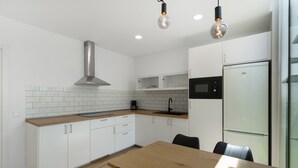 Una cocina moderna con armarios blancos, encimera de madera, campana extractora de acero inoxidable y microondas integrado.