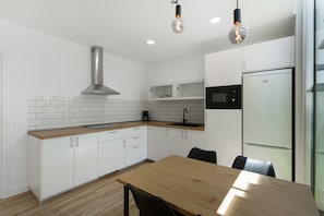 Eine moderne Küche mit weißen Schränken, einer Holz Arbeitsplatte, einer Edelstahl-Dunstabzugshaube und einer eingebauten Mikrowelle.