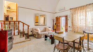 A living room with a sofa, coffee table, dining table, and chairs. There is a staircase leading to another room. - Apartment 'Elena Inn' with Private Terrace, Wi-Fi and Air Conditioning (Matino)