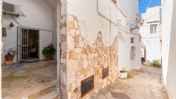A narrow street with stone walls, a white building with a door, and a potted plant. - Apartment 'Elena Inn' with Private Terrace, Wi-Fi and Air Conditioning (Matino)