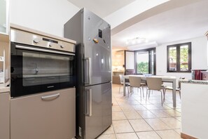Une cuisine équipée d’un four encastré, d’un réfrigérateur et d’un coin repas avec des chaises et une table.