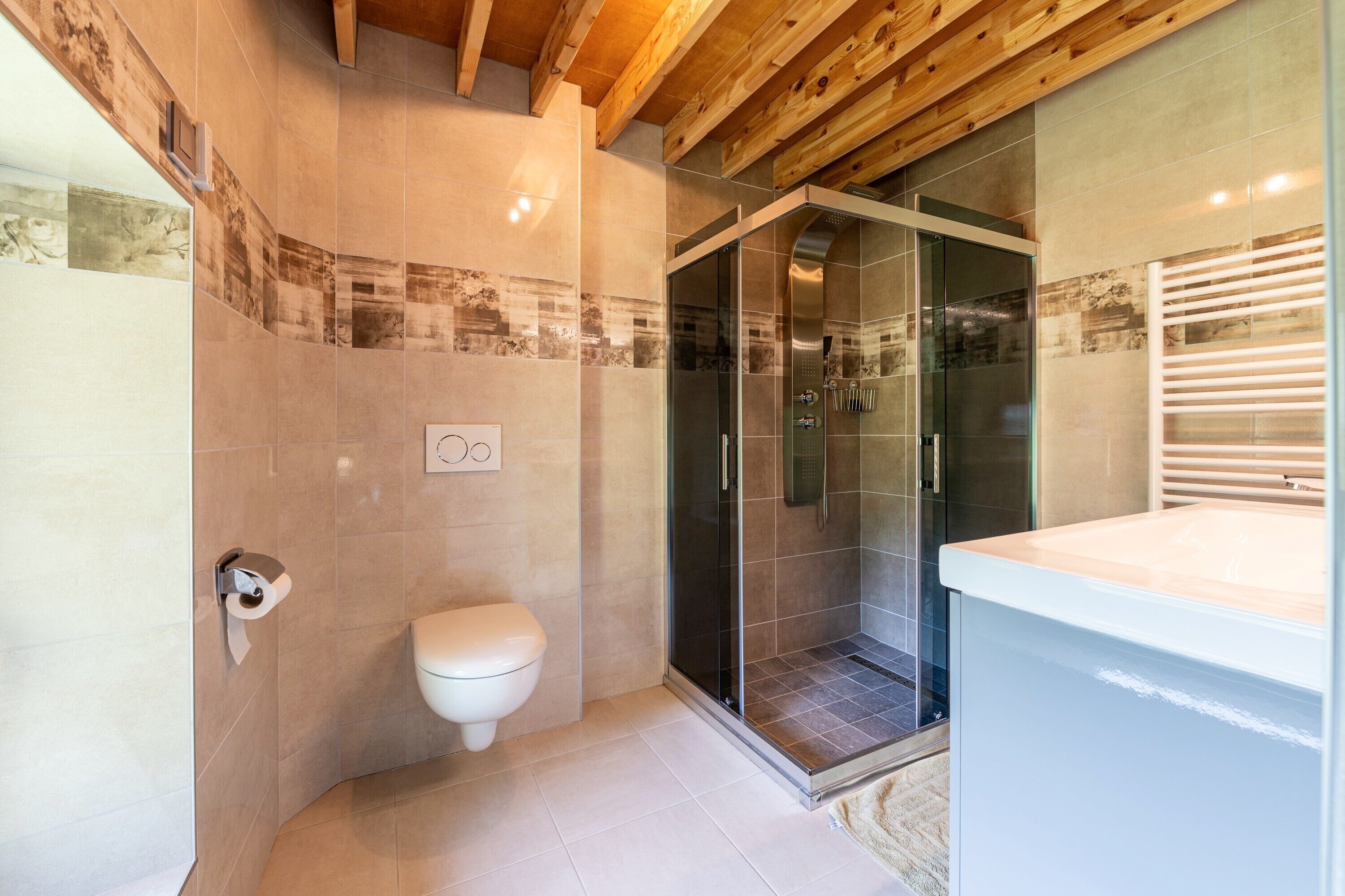 Een moderne badkamer met toilet, douche en wastafel.