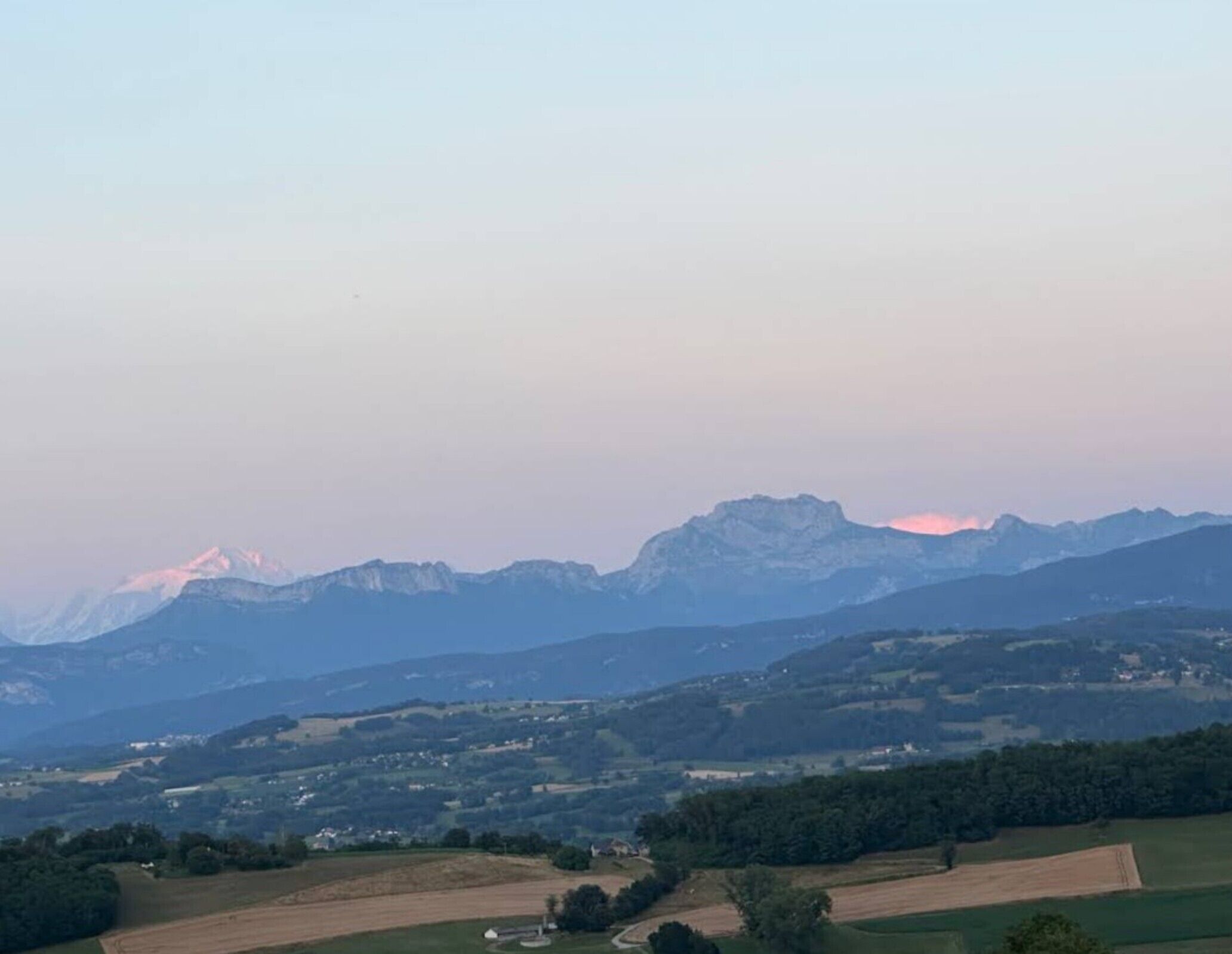 A mountainous landscape with a prominent peak, rolling hills, and scattered buildings.
