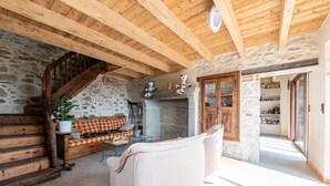 A rustic interior with a stone wall, wooden staircase, a sofa, and a dining table. - Bed and breakfast "Chambre Bleue" with Mountain View, Private Terrace and Shared Garden (Moye)