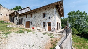 A stone building with a sloped roof, a gravel driveway, and a fenced area. - Bed and breakfast "Chambre Bleue" with Mountain View, Private Terrace and Shared Garden (Moye)