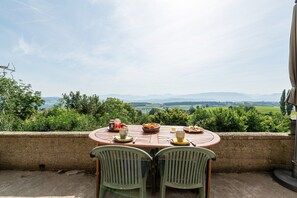 A table with chairs and a view of a green landscape. - Bed and breakfast "Chambre Bleue" with Mountain View, Private Terrace and Shared Garden (Moye)