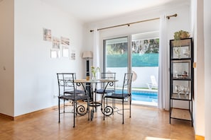 A dining area with a table and chairs, a lamp, and a view of a swimming pool.