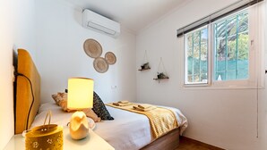 A bedroom with a bed, bedside table, lamp, air conditioner, window, and wall decorations. - Holiday Home 'Casa Cerro Del Aguila' with Mountain Views, Wi-Fi and Air Conditioning (CERROS DEL AGUILA)